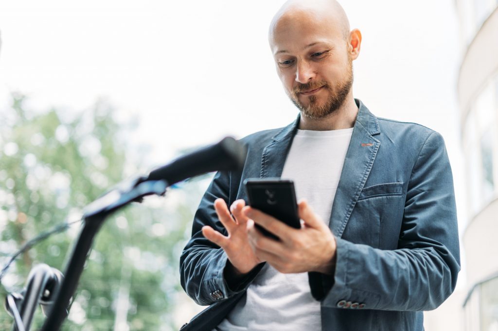 adult bald bearded man in blue suit with mobile on bicycle 1024x682 1