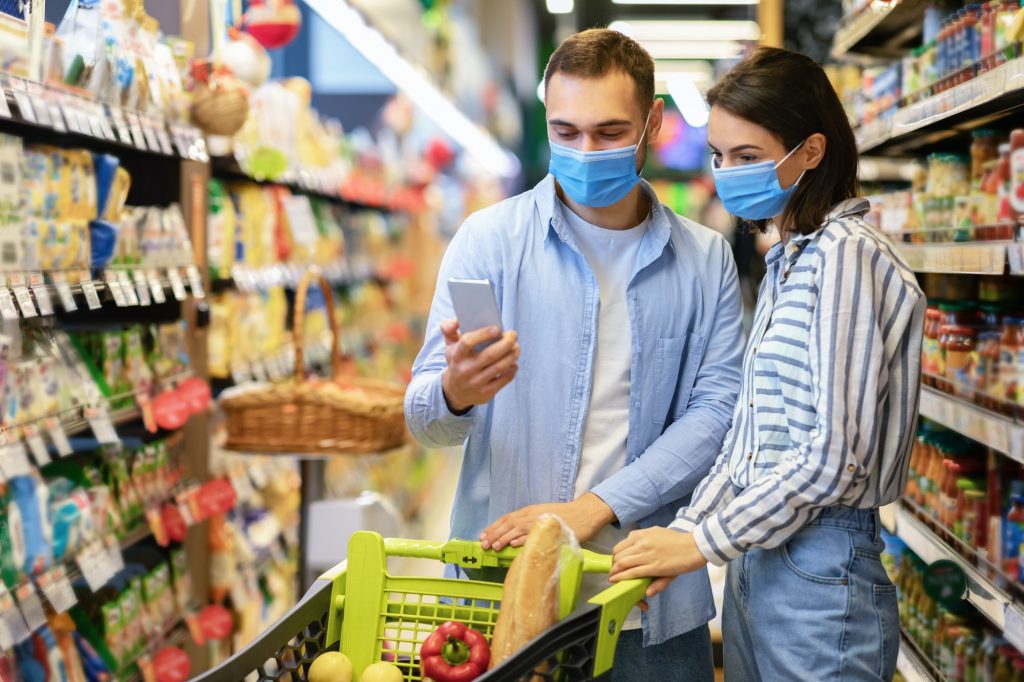 young couple in masks with phone shopping in supermarket 1024x682 1